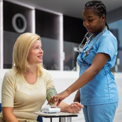 Infirmière mesurant la tension artérielle d'une collaboratrice lors d'un bilan de santé en entreprise