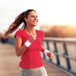 Femme souriante pratiquant la course à pied illustrant l'application WellLife et l'hygiène de vie